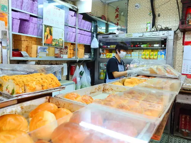 A lady serving behind a counter of cakes