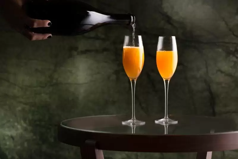 Champagne being poured into a champagne flute of Mimosa in Lucciola