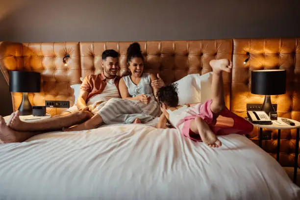 Couple playing with daughter on hotel bed