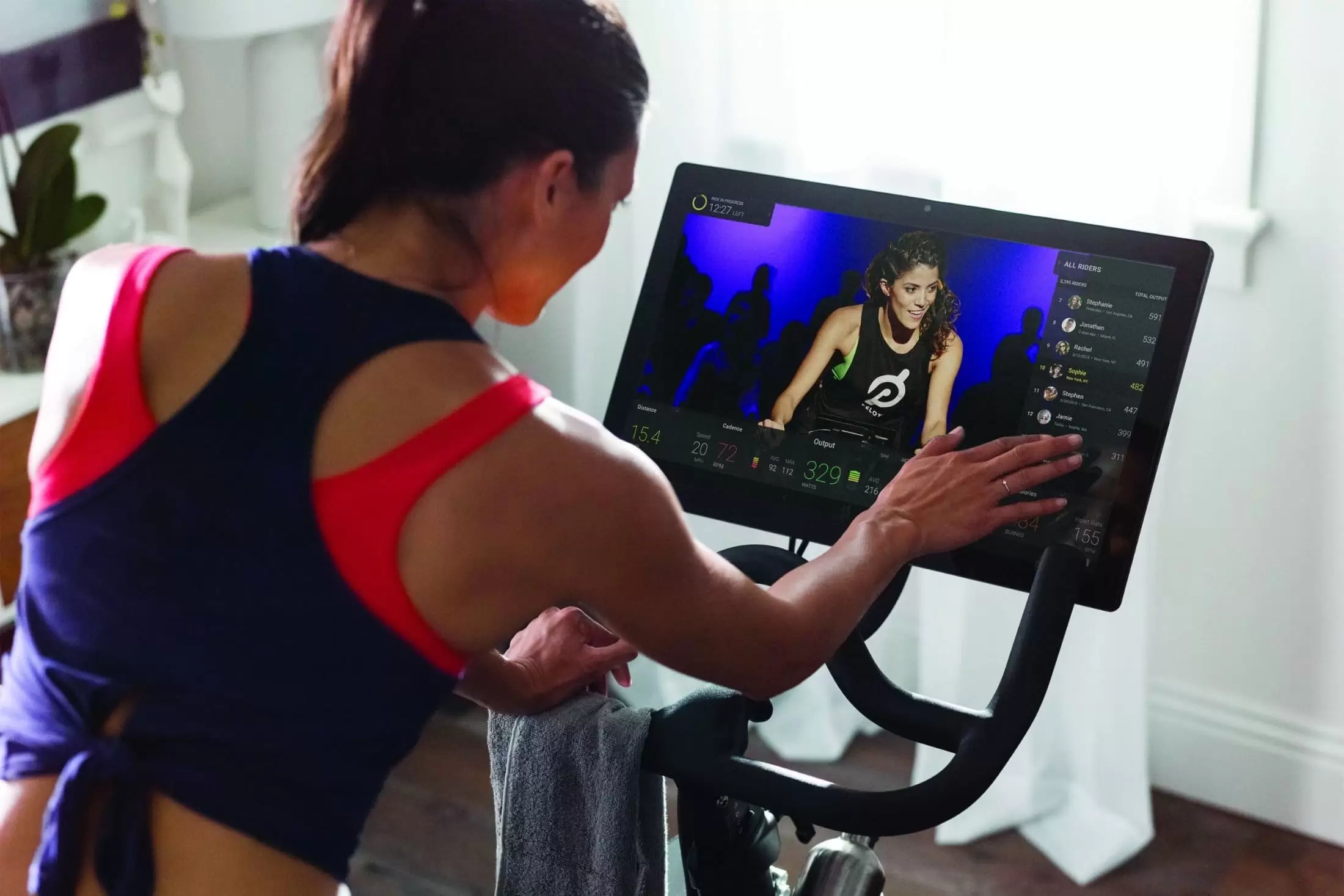 Woman adjusting the screen on Peloton Bike