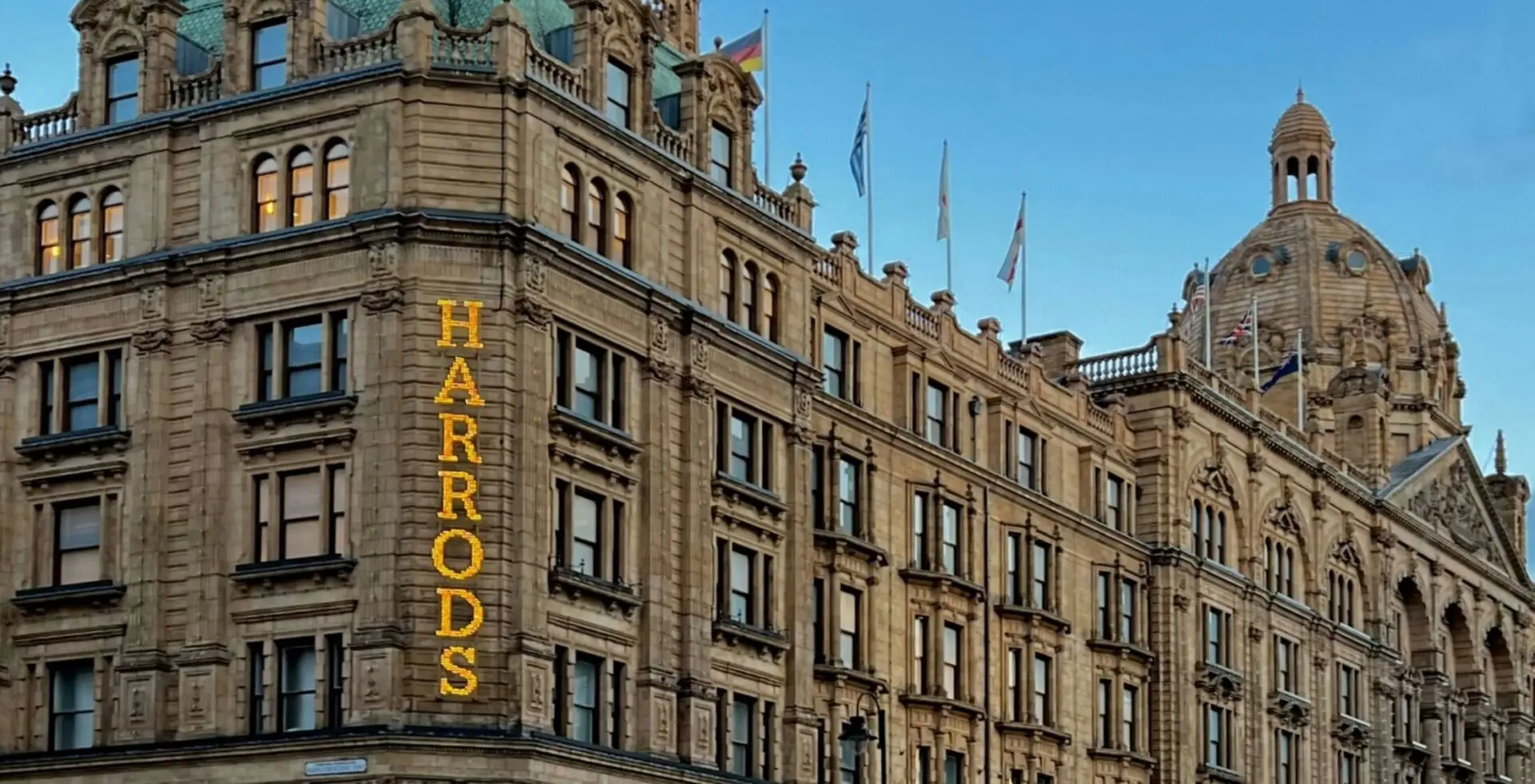Harrods in Knightsbridge, lit up against a dimming blue sky.